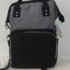 práctica mochila pañalera destaca por su diseño bicolor en tela gris texturizada
