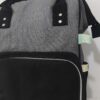 práctica mochila pañalera destaca por su diseño bicolor en tela gris texturizada