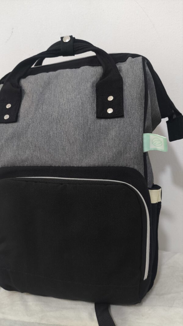 práctica mochila pañalera destaca por su diseño bicolor en tela gris texturizada