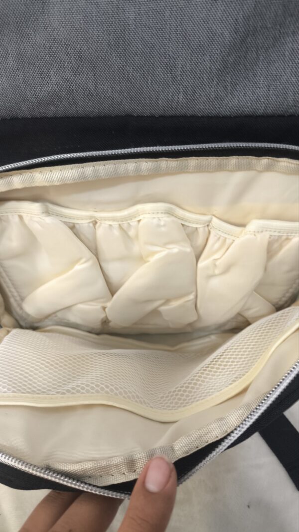 práctica mochila pañalera destaca por su diseño bicolor en tela gris texturizada