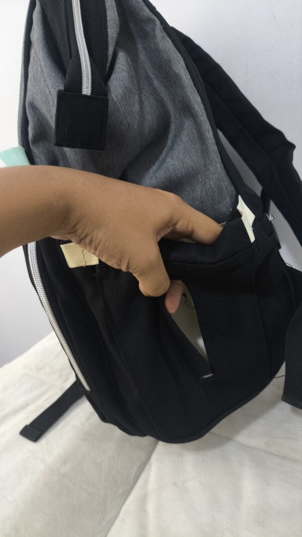 práctica mochila pañalera destaca por su diseño bicolor en tela gris texturizada