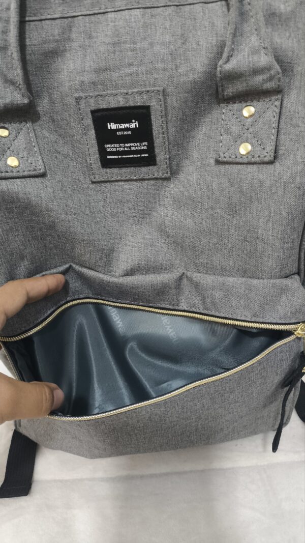 mochila y pañalera gris de lona de la marca Himawari con detalles dorados