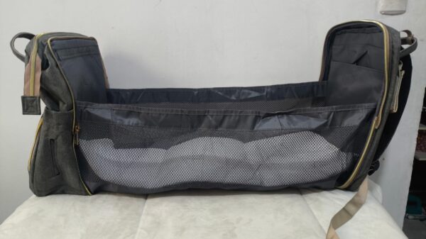 2026/10/1000786655-1.jpg mochila pañalera multifuncional de color gris melange con detalles dorados y un compartimento frontal y cambiador portátil